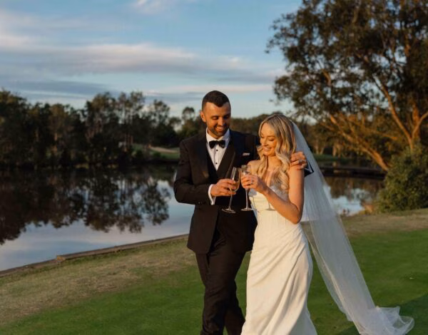 Venues Listing Category Mercure Kooindah Waters Resort Couple enjoying a sunset walk by the lake at Mercure Kooindah Waters Resort, Central Coast wedding venue.